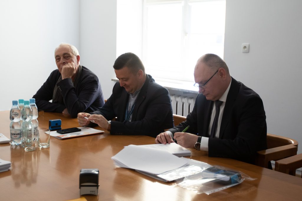 Podpisanie umowy: na zdjęciu przy stole siedzi trzech przedstawicieli Instytutu Badan Edukacyjnych.  Rozmawiają i podpisują dokumenty